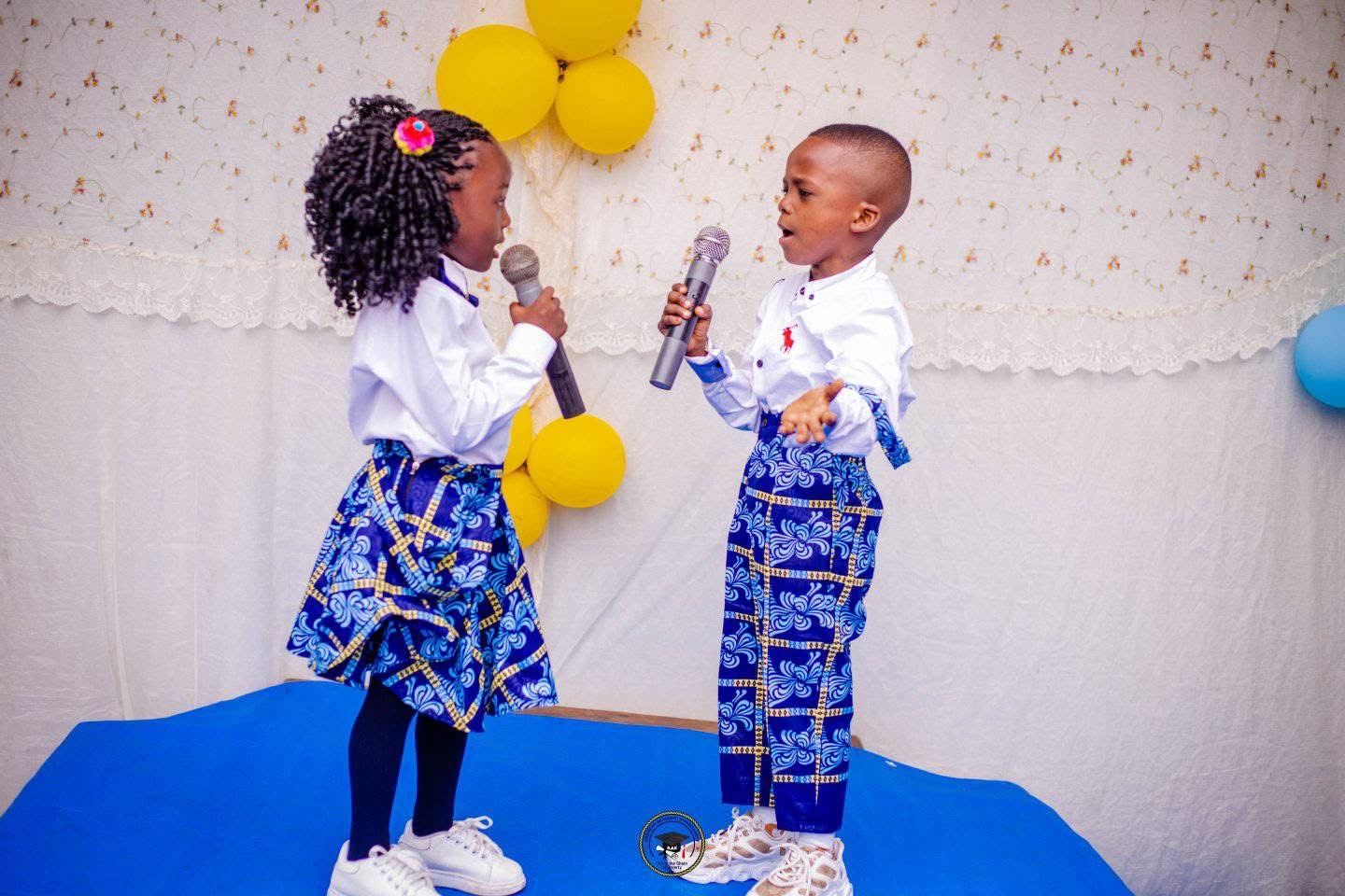 Two young AAE students speaking into microphones on stage